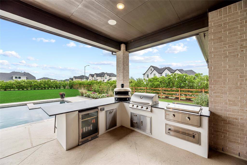 Enjoy entertaining outdoors with the patio kitchen, includes a grill, griddle, gas/wood-fired pizza oven, and beverage fridge.