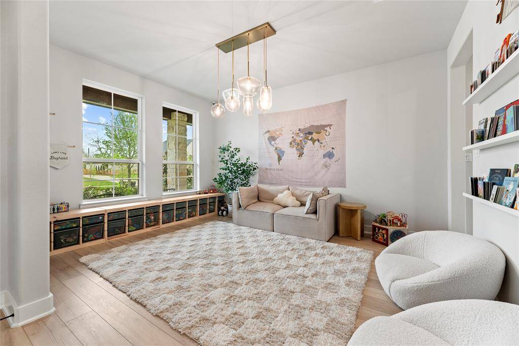 To the left of the entry is a formal dining space, here being used as a playroom.  The luxury fixture adds to the upscale atmosphere, with a dazzling chandelier casting a soft, flattering light over the space.