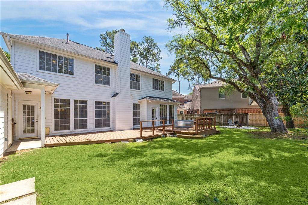 Impressive backyard featuring a large deck, cowboy pool, cozy fire pit, and plenty of lush green space.