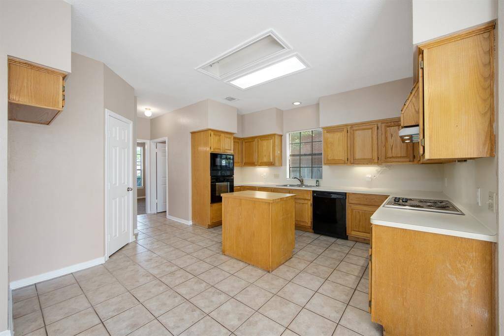 Bright and spacious kitchen featuring natural wood cabinetry, a central island, and ample counter space.