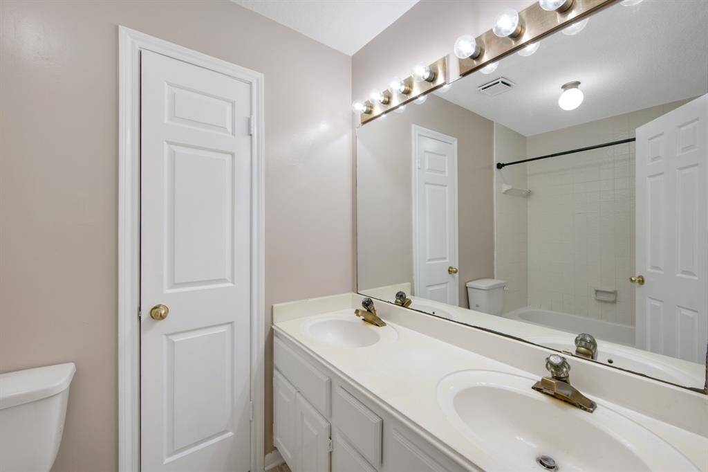 Bright full bathroom featuring a double vanity with large mirror and ample storage. Includes a tub/shower combo and neutral tones for a clean look.