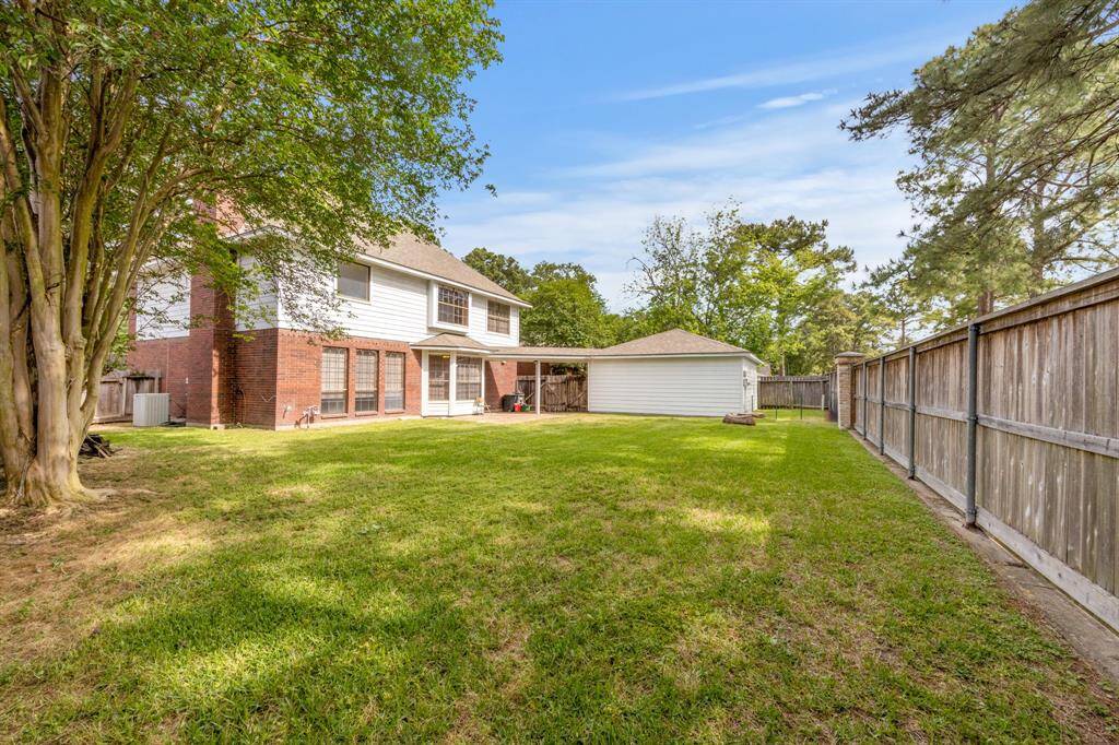Spacious fenced backyard with mature trees, ideal for outdoor gatherings or play.
