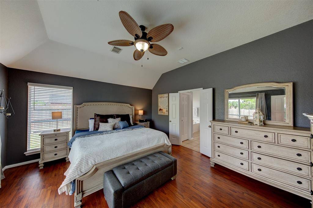 King size primary suite with relaxing colors and tall ceiling.