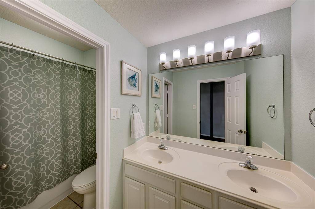 Bright full bath with tub shower and double sinks on first floor.