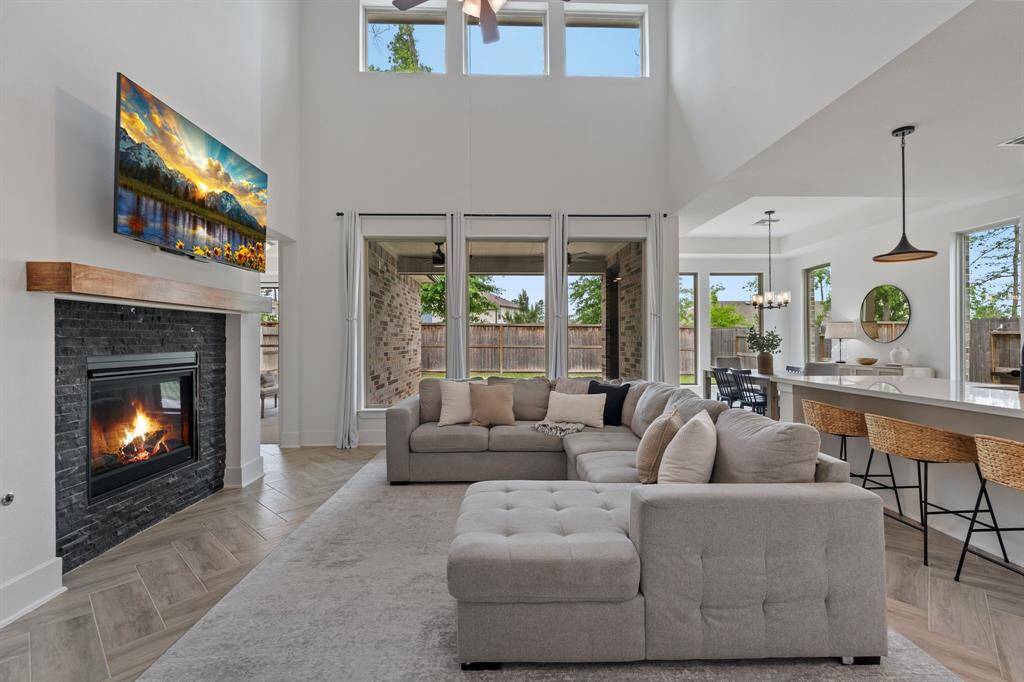 Experience a bright and airy living space with high ceilings and large windows. Enjoy a cozy fireplace with a custom mantle, modern open-plan design, and a comfortable seating area—perfect for entertaining.
