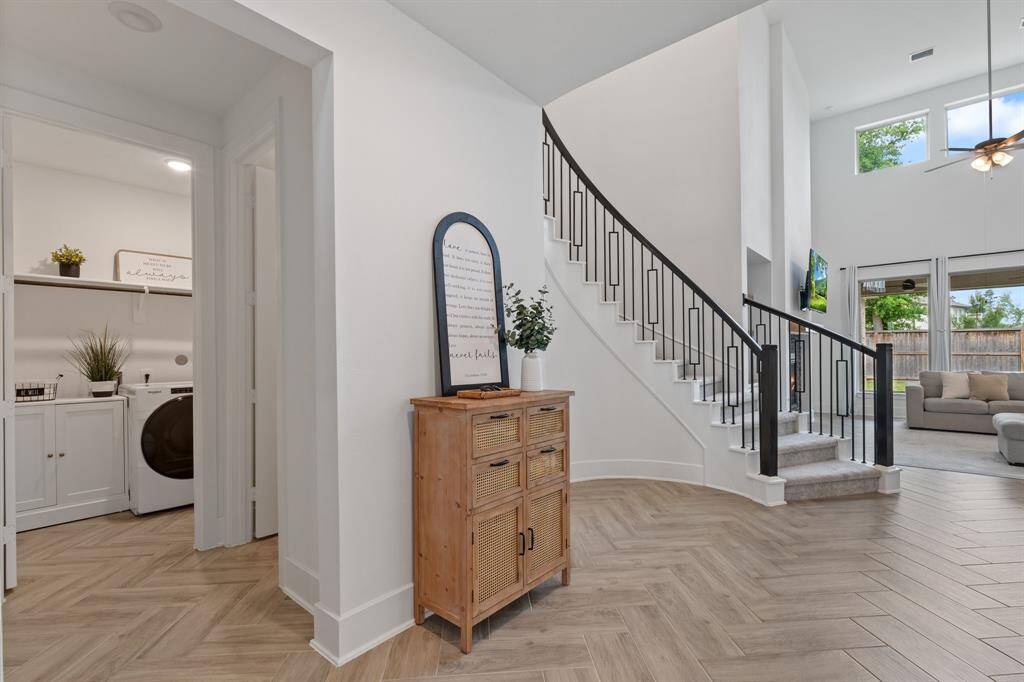 This photo showcases a bright, open entryway with a modern staircase and high ceilings.