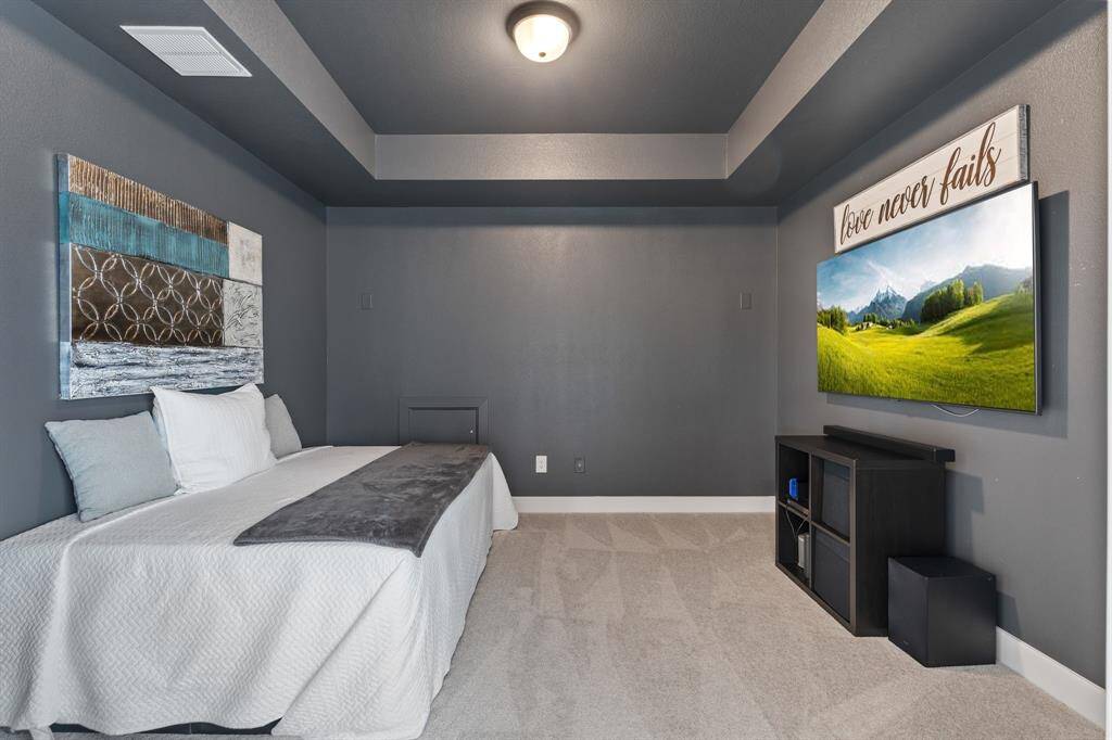 This inviting media room boasts elegant dark gray walls and a stylish tray ceiling, ideal for both relaxation and entertainment.