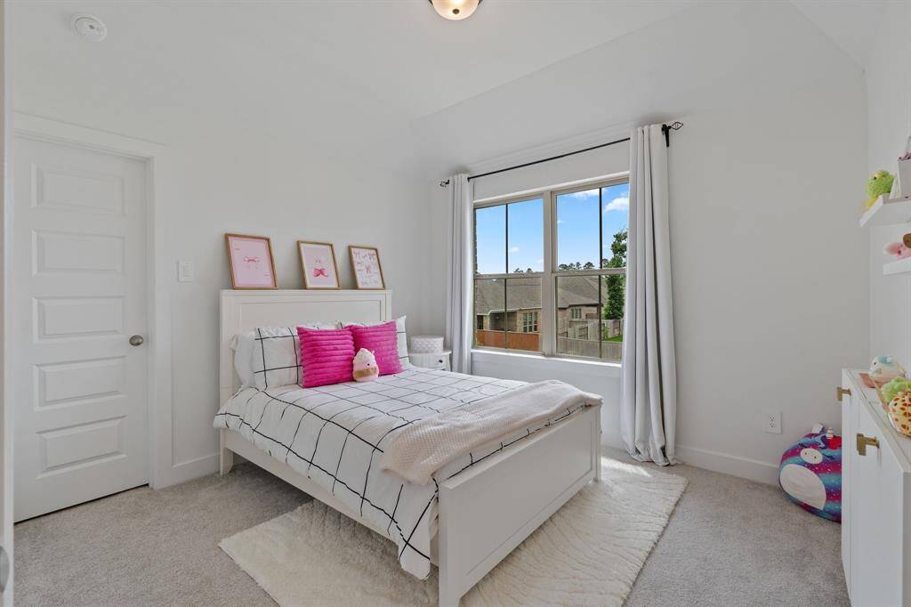 This inviting bedroom boasts plush carpeting and abundant natural light from a large window, ideal for a child's room or guest retreat.