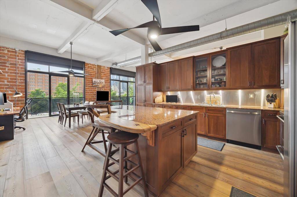Spacious kitchen with island has stainless steel appliances and backsplash along with granite countertops.