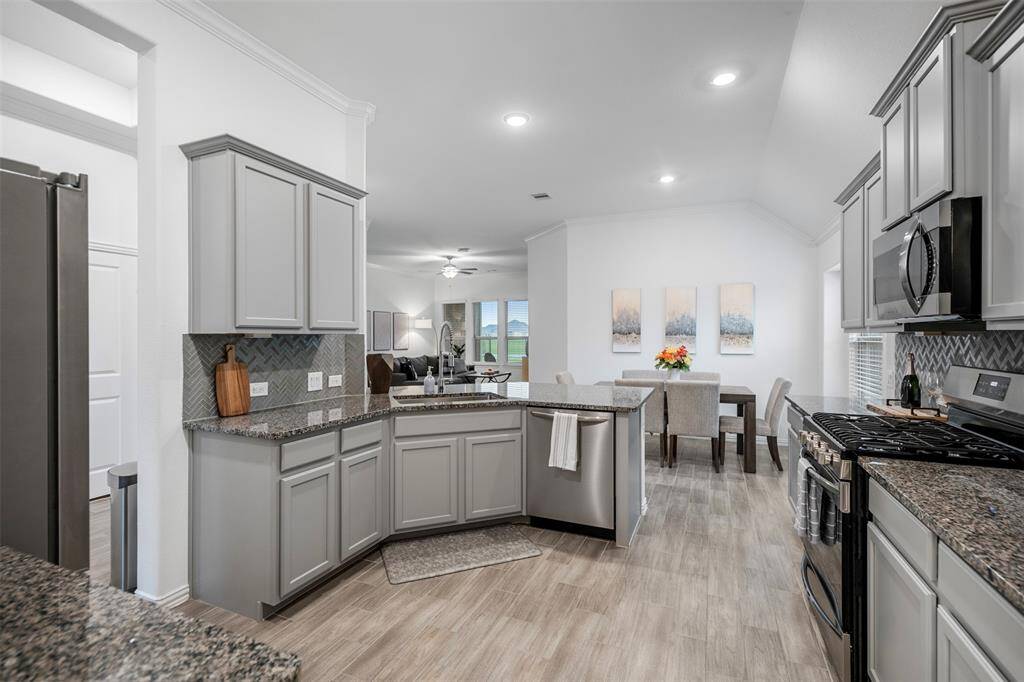 The kitchen is open to the breakfast nook/living room and boasts granite countertops, gray cabinets and an oversized sink.