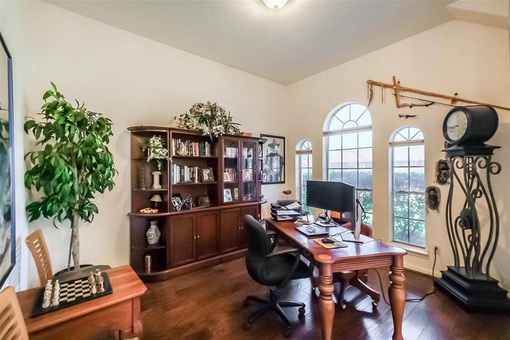 The room is well-lit by natural light from the arched windows, creating a bright and inviting workspace. Dark wood flooring provides a stylish contrast.