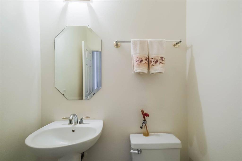 Powder room features pedestal sink and mirror accent. Located just off the right of the front foyer.