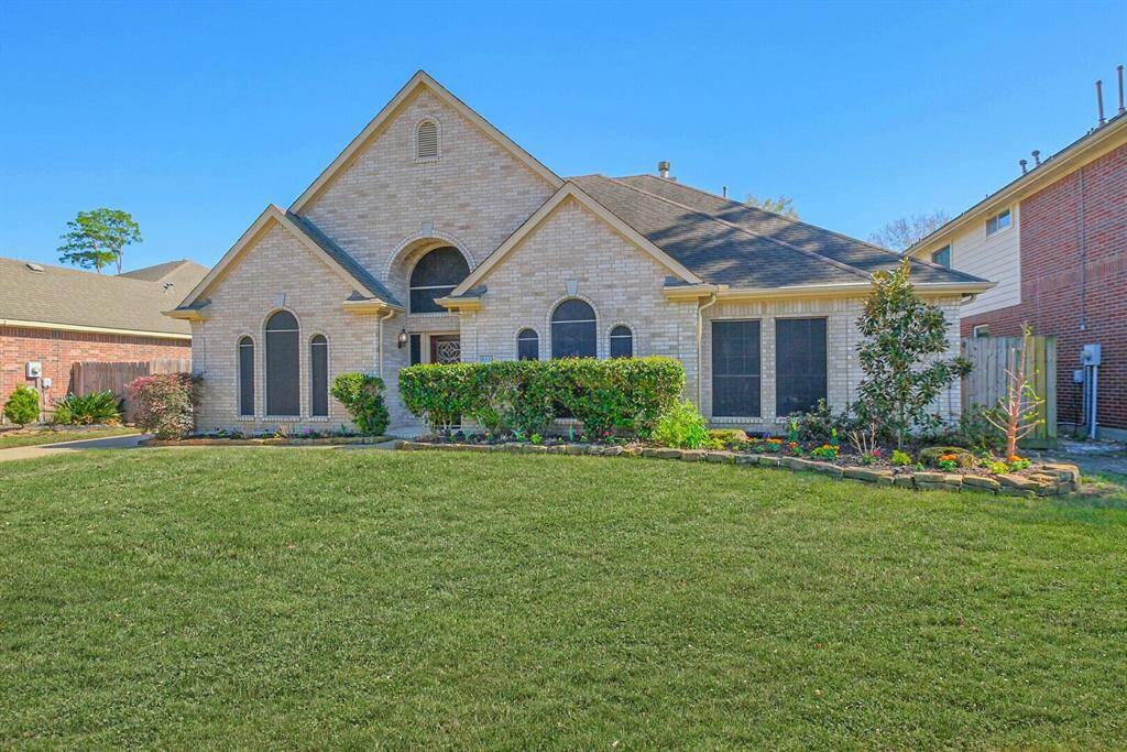This inviting home features a well-maintained brick exterior with arched windows, a manicured lawn, and tasteful landscaping. Its classic design offers great curb appeal in a pleasant neighborhood setting.