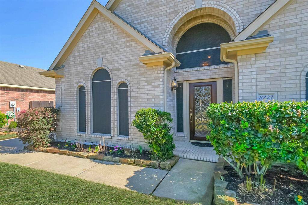 The entryway is framed by neatly trimmed hedges and a small garden, offering a welcoming curb appeal.