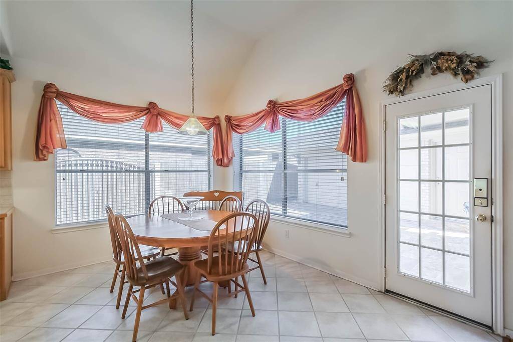 Breakfast nook with large windows, elegant drapery, and a cozy dining set. Features tile flooring and a glass door leading outside, creating a welcoming, airy space.