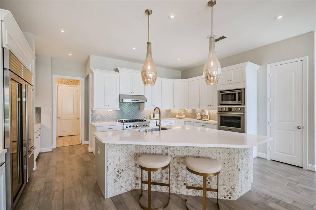 Tons of cabinet and storage space, including a deep walk-in pantry. This lovely island with breakfast bar seating has 2-tone cabinets on one side and complimentary tile on the seating side. Custom pendant lighting and newly installed LED ceiling lights.