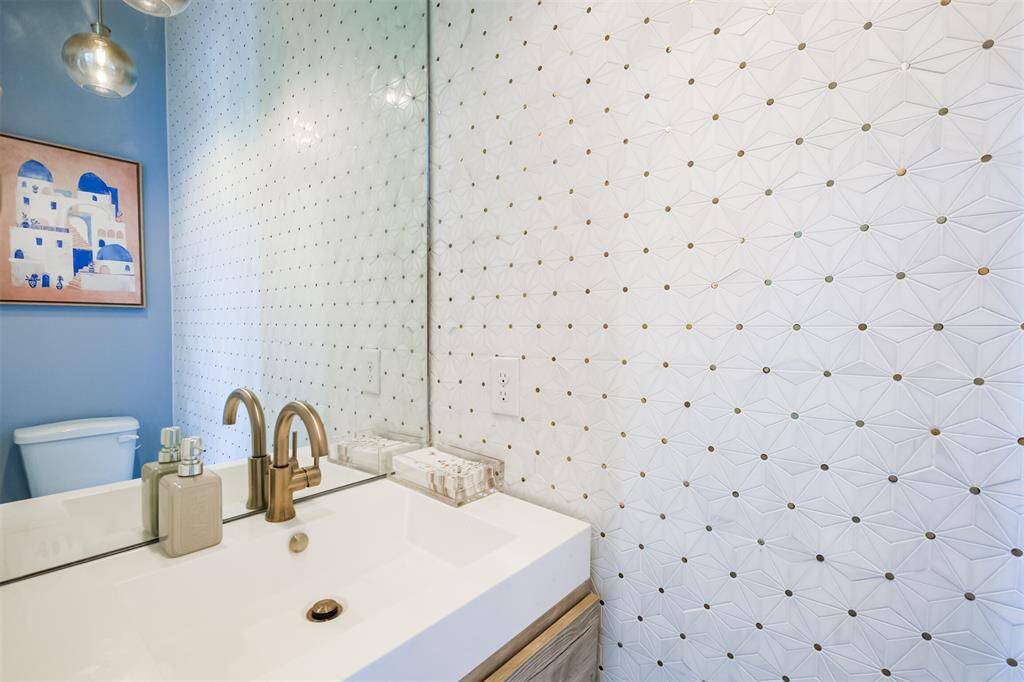 The guest half bath is conveniently located off from the living room. With white & gold custom tile, pendant lighting and champagne fixtures, it's the prettiest 1/2 bath you'll ever see!
