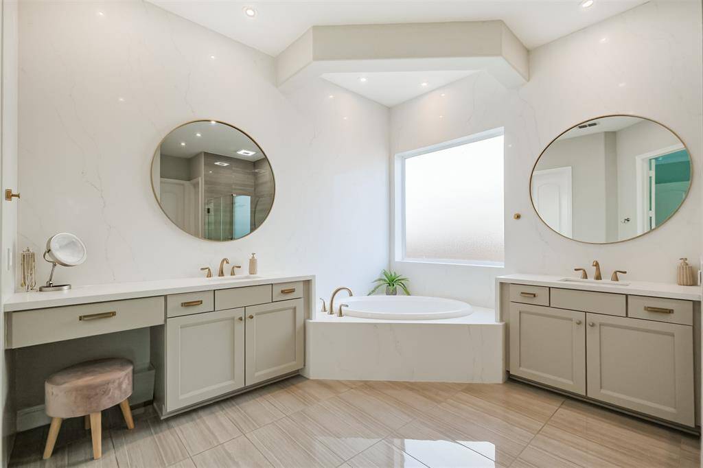 The primary bathroom boasts double vanities and a large corner soaking tub. Just add bubbles and relax!