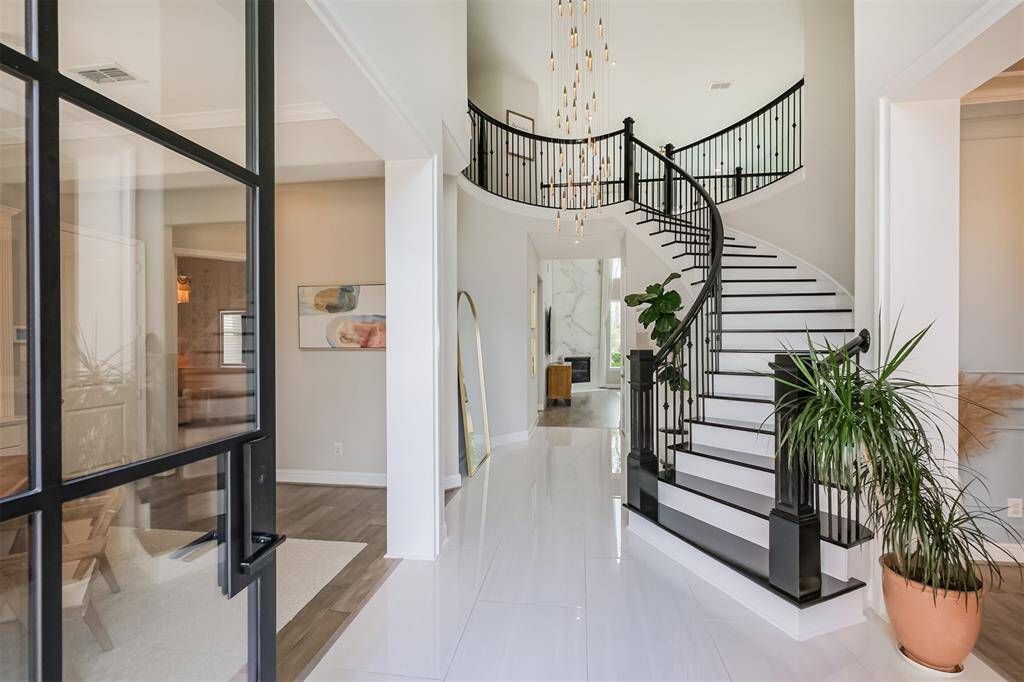 Enter through the custom black iron door that was added by the current owners into the two story entry. The foyer was updated with oversized 24"x48" tile, custom oak winding stairs with white risers & black gloss treads and an eye catching chandelier.