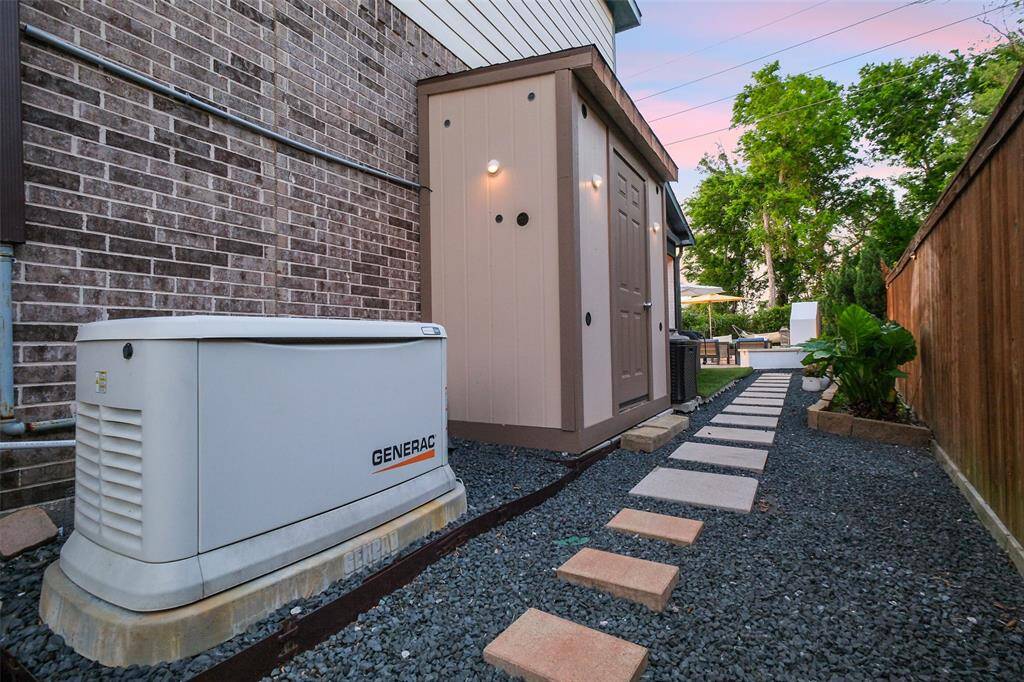 View of the 22Kw whole home Generac generator and storage shed on the side of the home. Crushed rock and paver steps are to be found on both sides of the home.