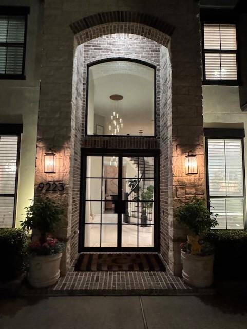 A night shot of the amazing entryway showcasing the contemporary black iron and glass double doors which were installed in 2023.
