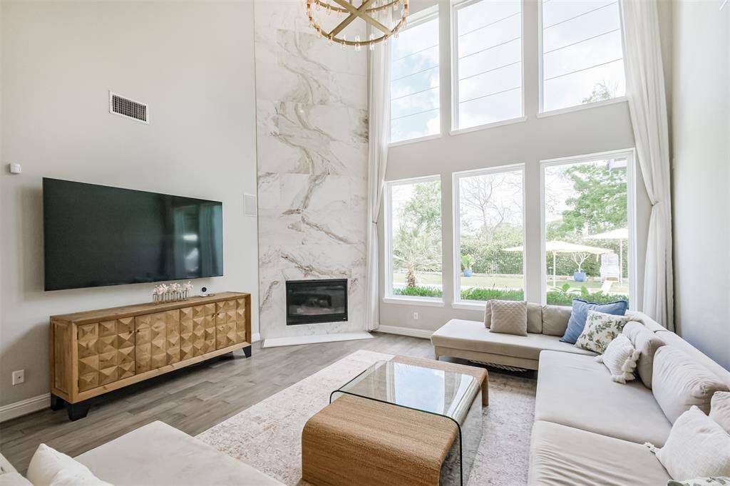 In the gorgeous two story family room the fireplace was updated with 21 feet of large marble tiles which complement the upgraded LPV flooring. Floor to ceiling windows provide tons of natural light and expansive views of the beautiful backyard and greenspace beyond.