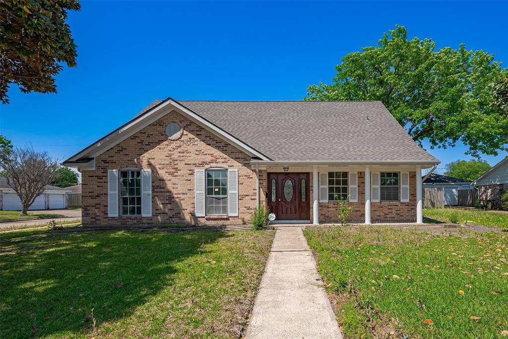 Charming brick home with a welcoming front porch, featuring a well-maintained lawn and mature trees. The entryway boasts decorative glass, and large windows provide ample natural light.