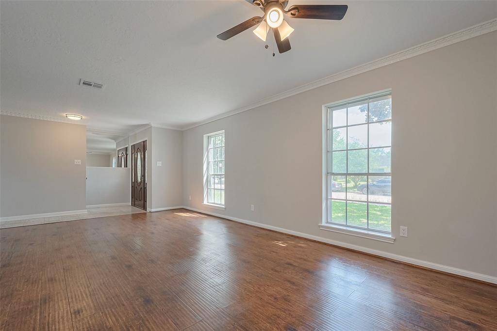 Bright and spacious formal dining room could be your second living space with large windows, hardwood floors, and a ceiling fan. Neutral walls and crown molding add elegance.