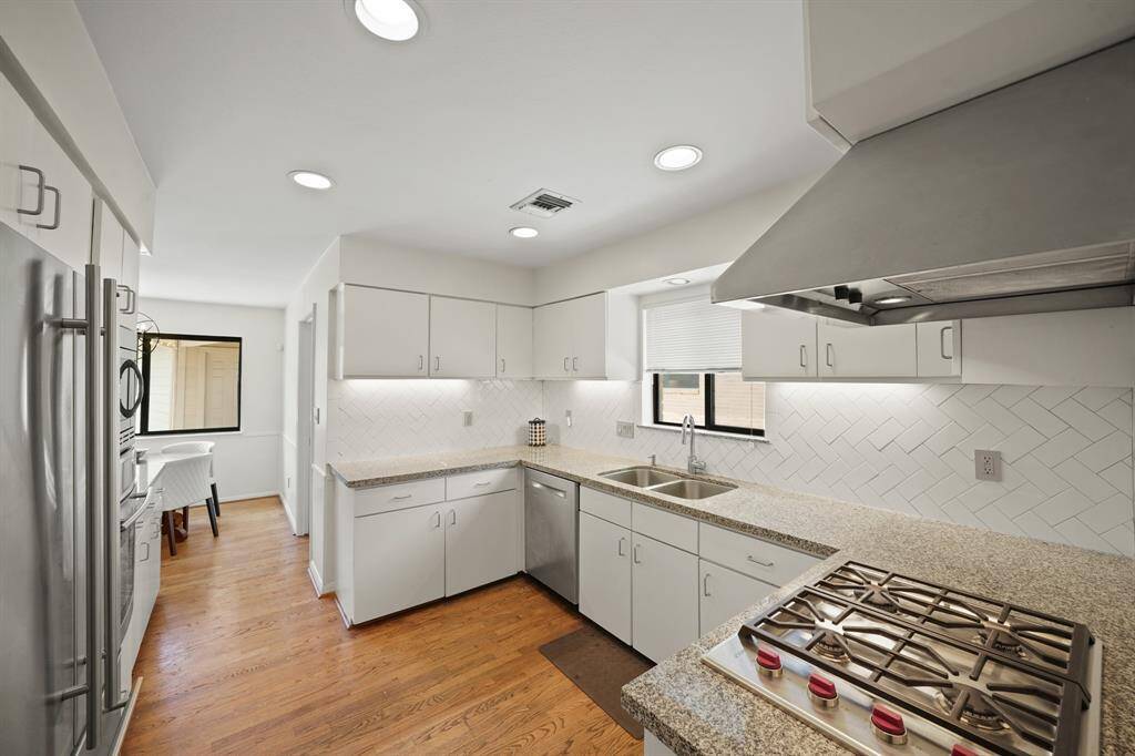 The Kitchen boasts Granite Countertops, Herringbone Set White Subway Tile Backsplash (2019*), White Painted Cabinets/Drawers (2019*), Wolf 4 Burner Gas Range (2019*), Stainless Steel Range Hood, Bosch Stainless Steel Dishwasher (2019*), Undermount Stainless Steel 2 Basin Sink (2019*), Grohe Polished Chrome Goose Neck Faucet with Pull out Spray (2019*), Polished Chrome Soap Dispenser (2019*), Granite Topped Window Sill, and Under Cabinet Lighting (*per Seller).