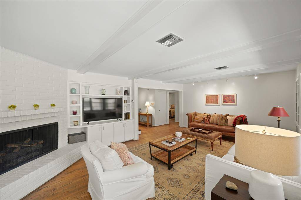 This Well Designed Living Area features a Corner White Painted Brick Fireplace with Gas Logs, Hearth and  Mantle---such a Wonderful Focal Point for the Room.  Enjoy the Built in Entertainment Center with Shelves and Cabinets.  The Entertainment Center was modified in 2019 (per Seller) to accommodate a 65" Flat Screen TV.