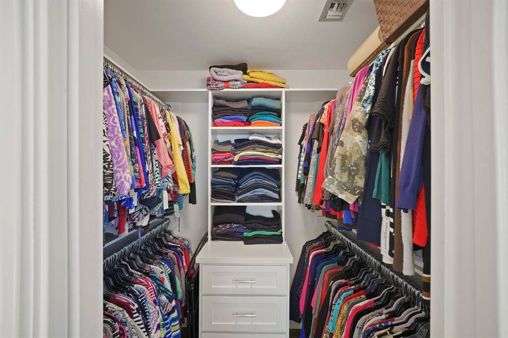 The Walk in Primary Closet (Approximately 6'1" x 5') features Newly Installed Carpet (4/2025*), Built-on-Site Soft Close Built in Drawers with Open Shelves (2019*), Multiple Hanging Rods, and a Flush Mount Light Fixture (*per Seller).