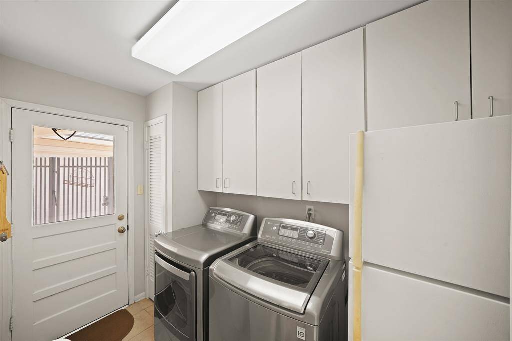 The Laundry Room features Grey Tile Floors,  Built in Cabinets, Full Size LG Washer & Dryer (Remain per Seller), Utility Closet (for Brooms, Mops etc.), and a Door (with Glass Inset) that opens to the Breezeway, OutdoorPatio, Pool, and the Yard.  Seller states the Secondary Refrigerator in the Laundry Room remains with the Home.