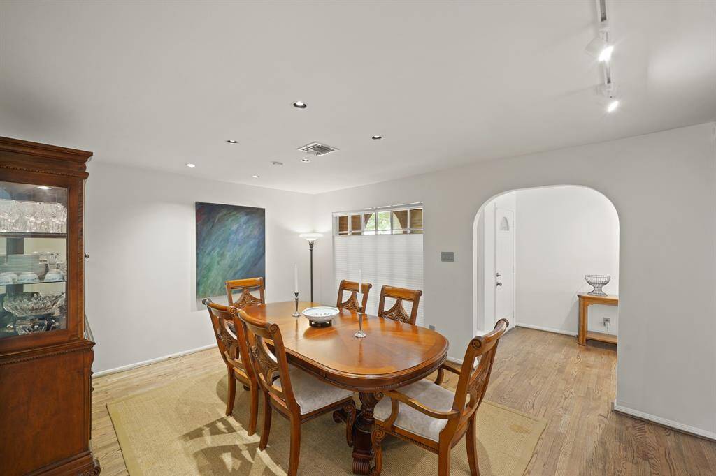 The Dining Area features Red Oak Hardwood Floors (2019 per Seller) and Halogen Art Spot Lighting.  A Wall of Picture Sized Windows (with Pleated Shades) view the Private Front Courtyard.