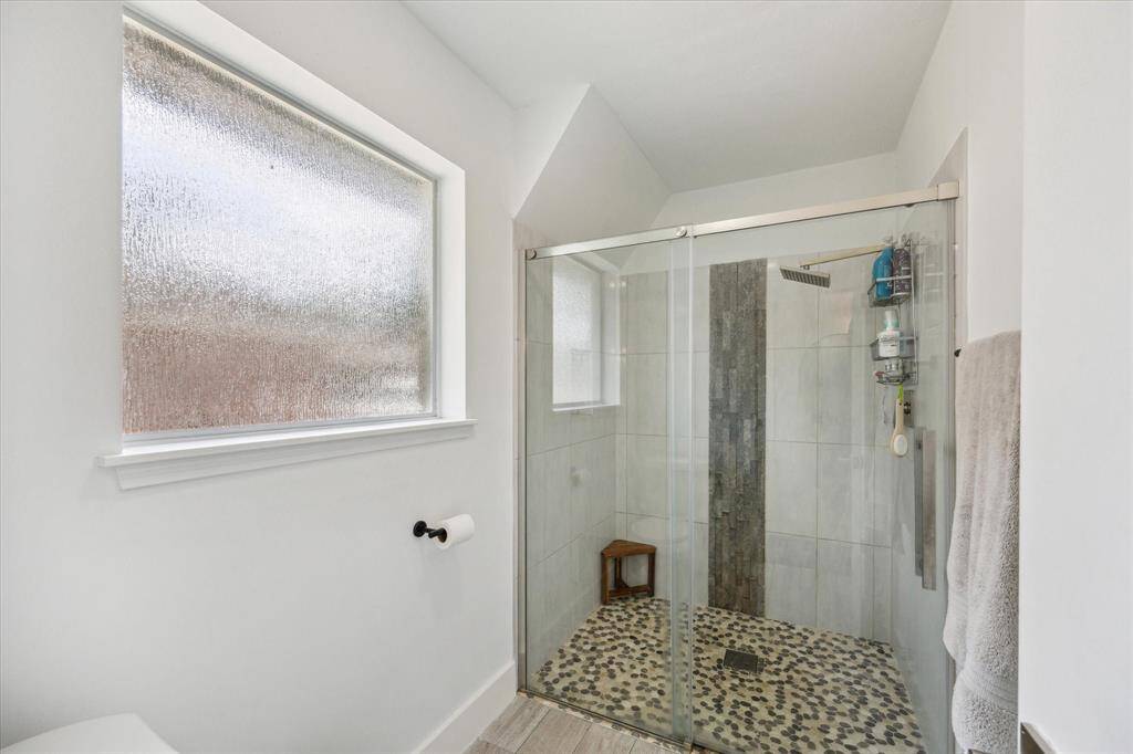 Large walk-in shower with glass door and tile surround.
