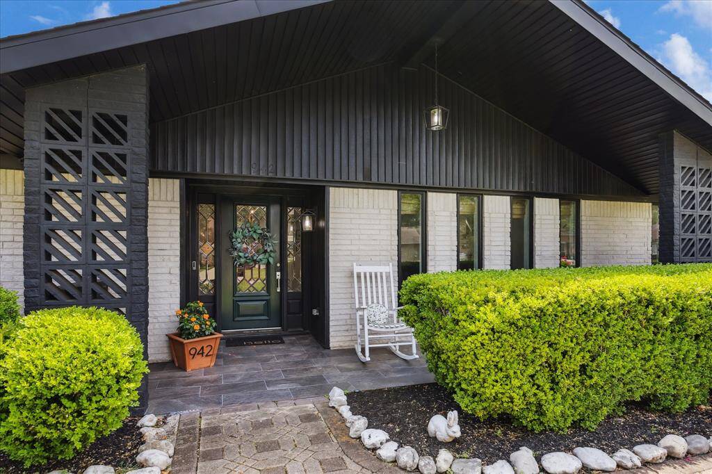 Adorable front porch entry surrounded by lush landscaping