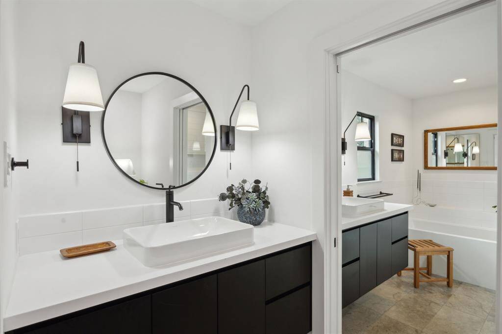 Primary bath offers separate sink areas, tasteful sconces, and Kohler plumbing fixtures.