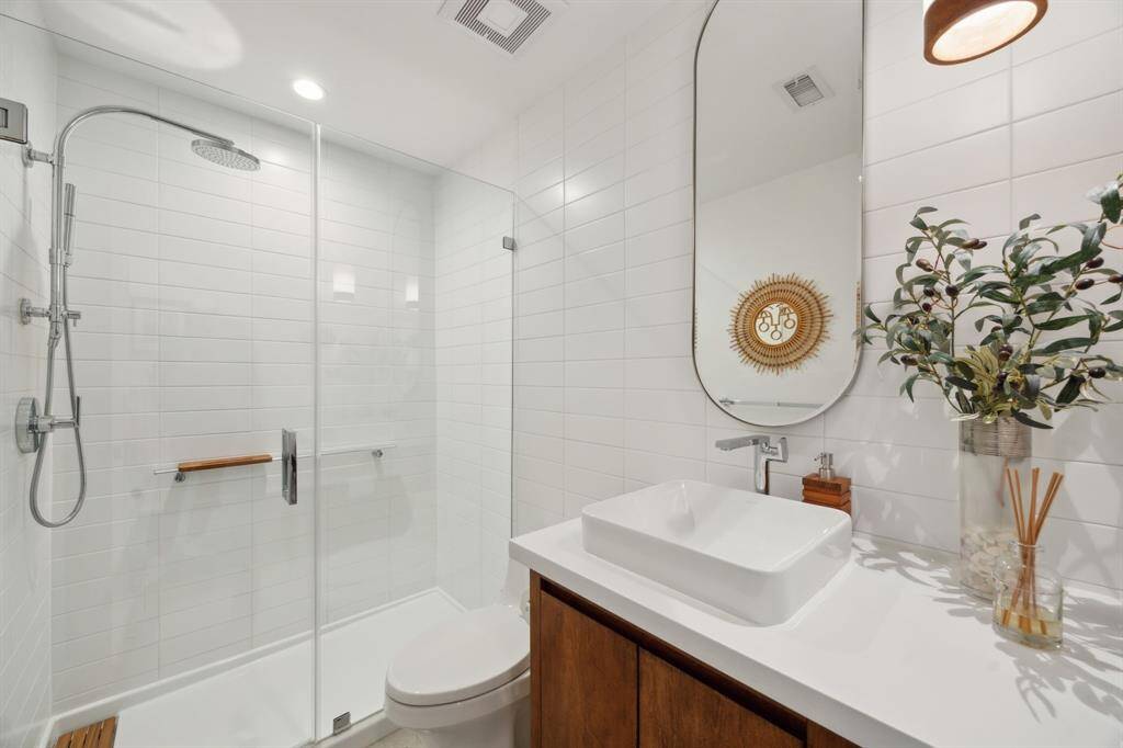 Guest bath with floor to ceiling subway tile, vessel sink, and frameless glass shower.