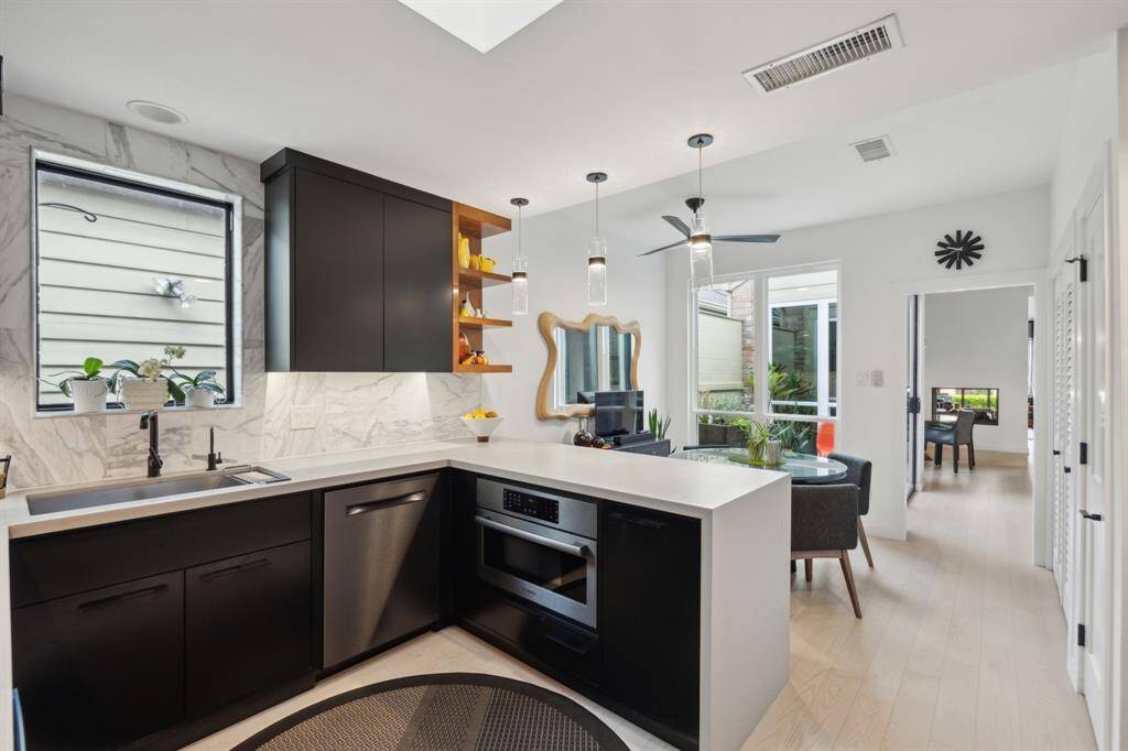 Another perspective of the kitchen showing a view of the striking backsplash and bright breakfast room.