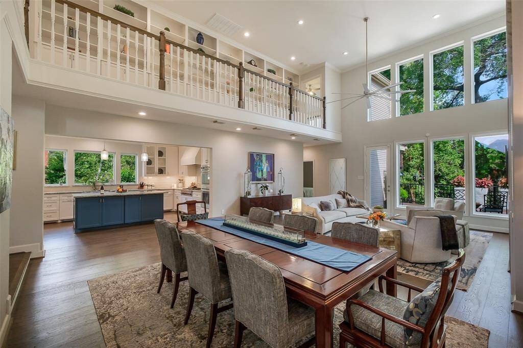 An elegant open-concept layout connects the living, dining, and kitchen areas, framed by dramatic double-height ceilings and gallery style walls.