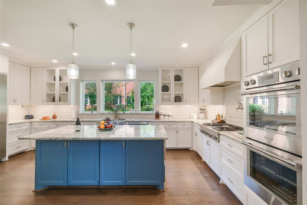 Expansive windows with motorized shades bathe the space in natural light, while thoughtful design details-under-cabinet lighting, double ovens and walk-in pantry-seamlessly blend luxury and function.