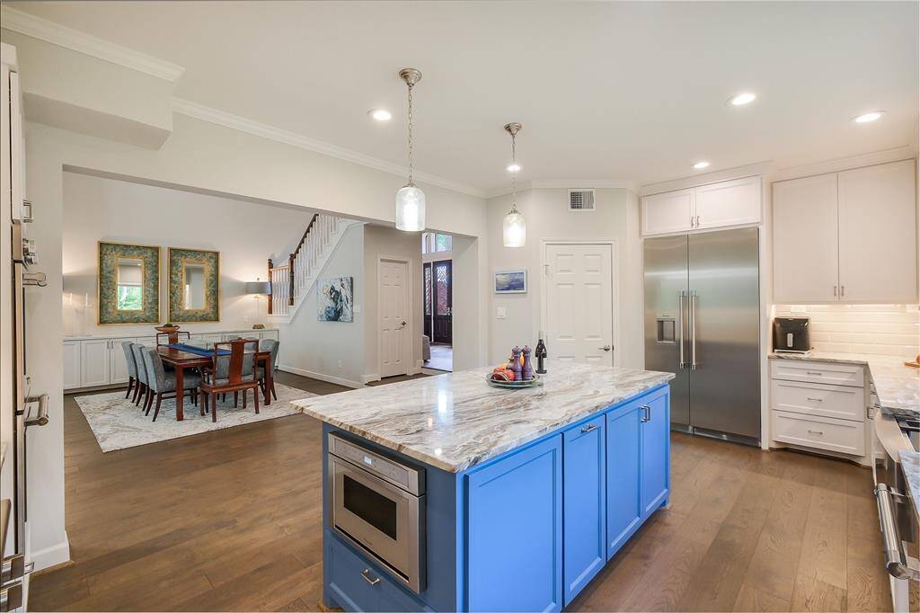 A striking blue island features marble counters, a built-in microwave, and generous storage-blending form and function perfectly.