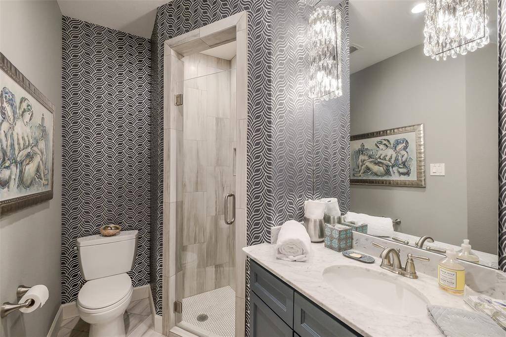 First-floor guest bath features dramatic designer wallpaper, a frameless walk-in shower, custom vanity, and polished finishes. Beautiful!