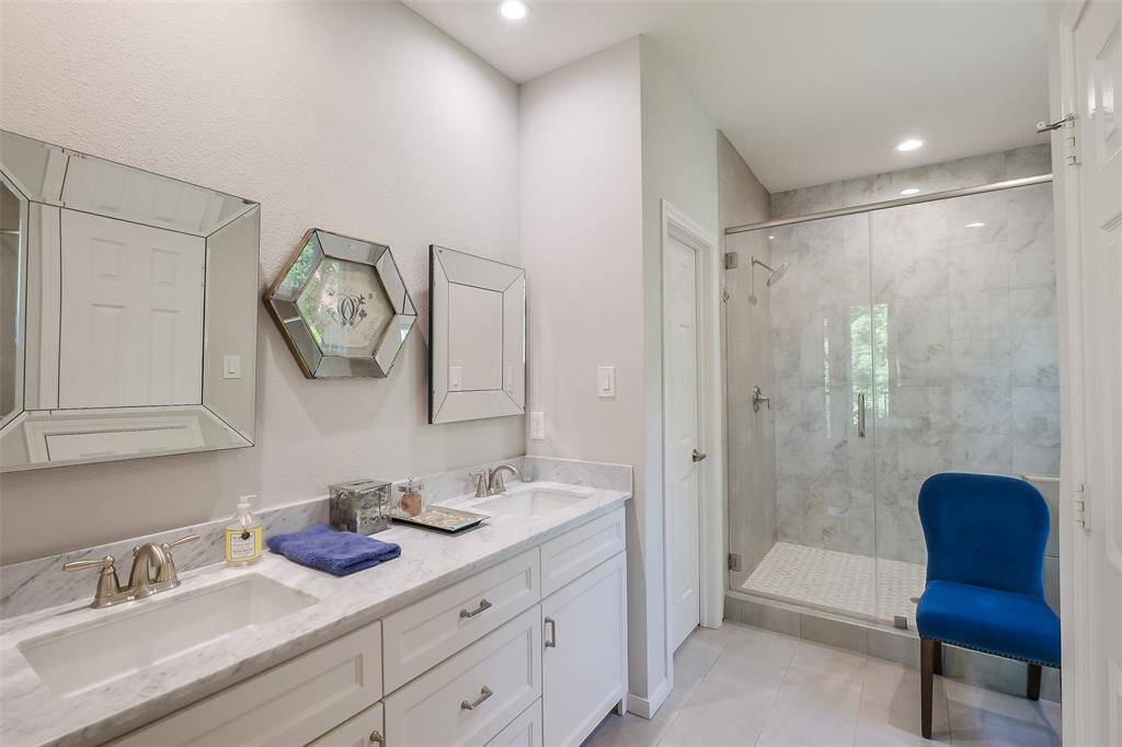 The primary bath features dual sinks, marble countertops, and modern lighting for a spa-like atmosphere.