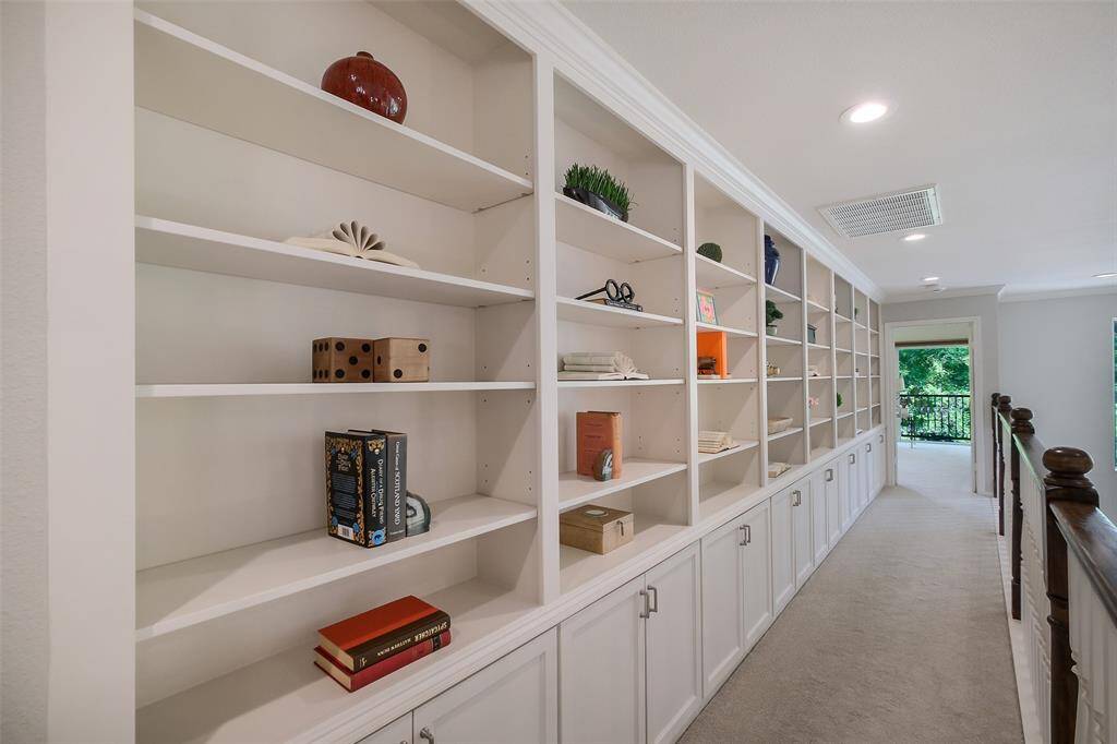 A loft-style hallway library with custom built-ins provides gallery-like display space and abundant storage.