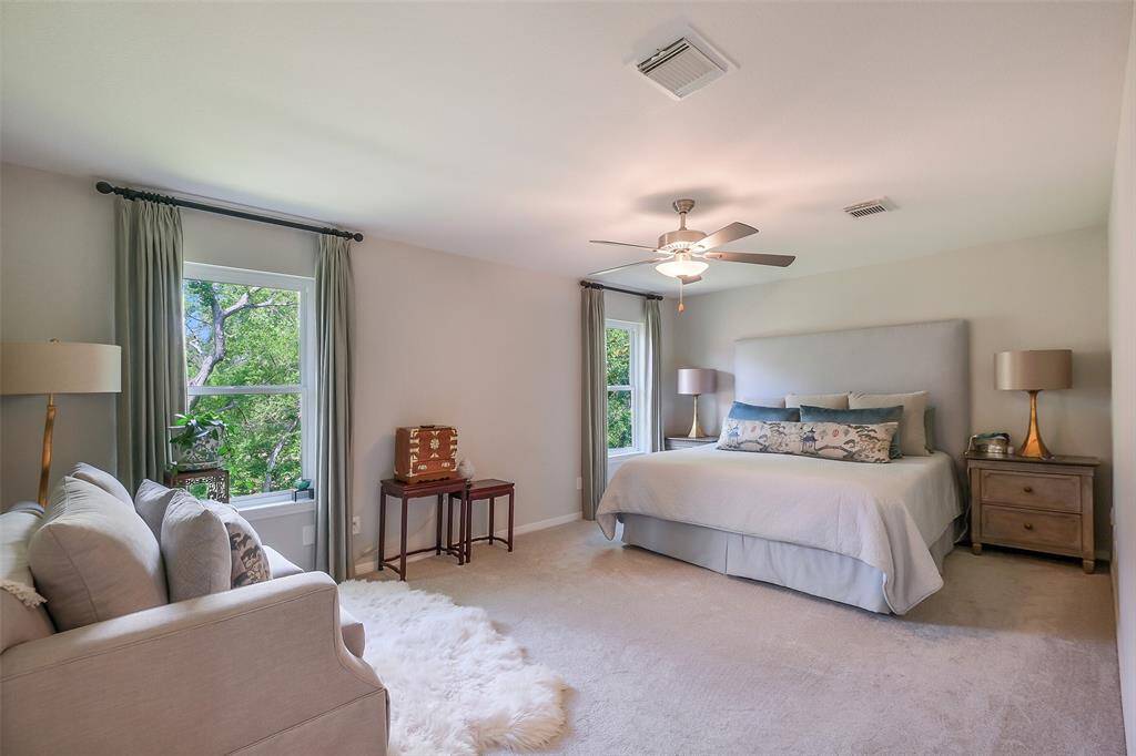 The second-floor primary suite offers a generous footprint with room for a sitting area and treetop views, along with an en-suite bath and two large walk-in closets.