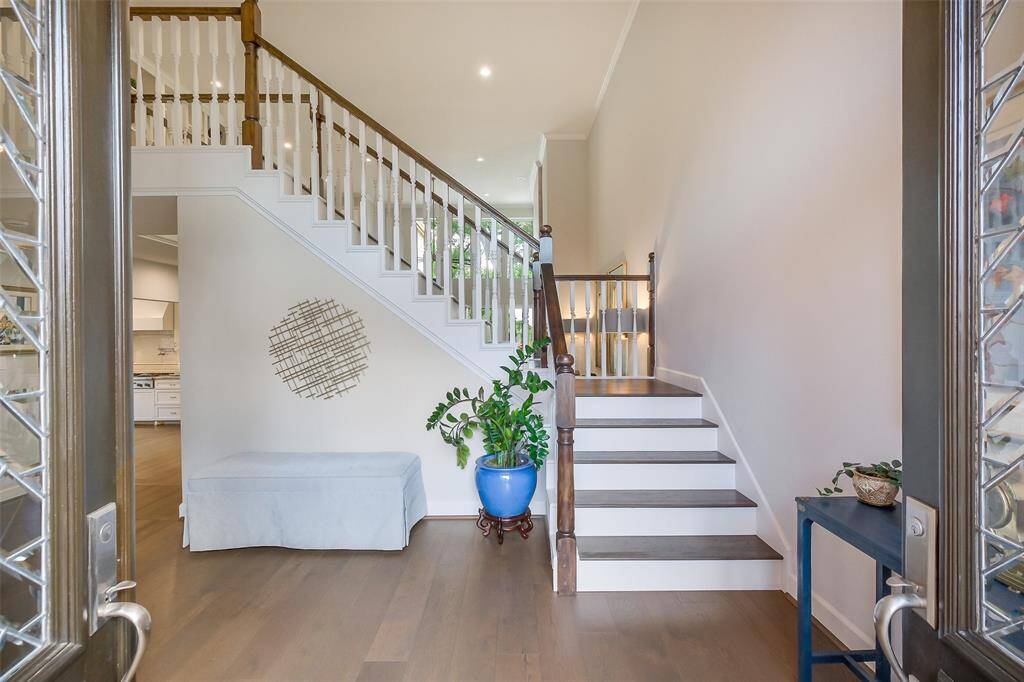 The wide staircase with custom railings rises gracefully from the light-filled entryway, offering a seamless flow into the main living spaces.