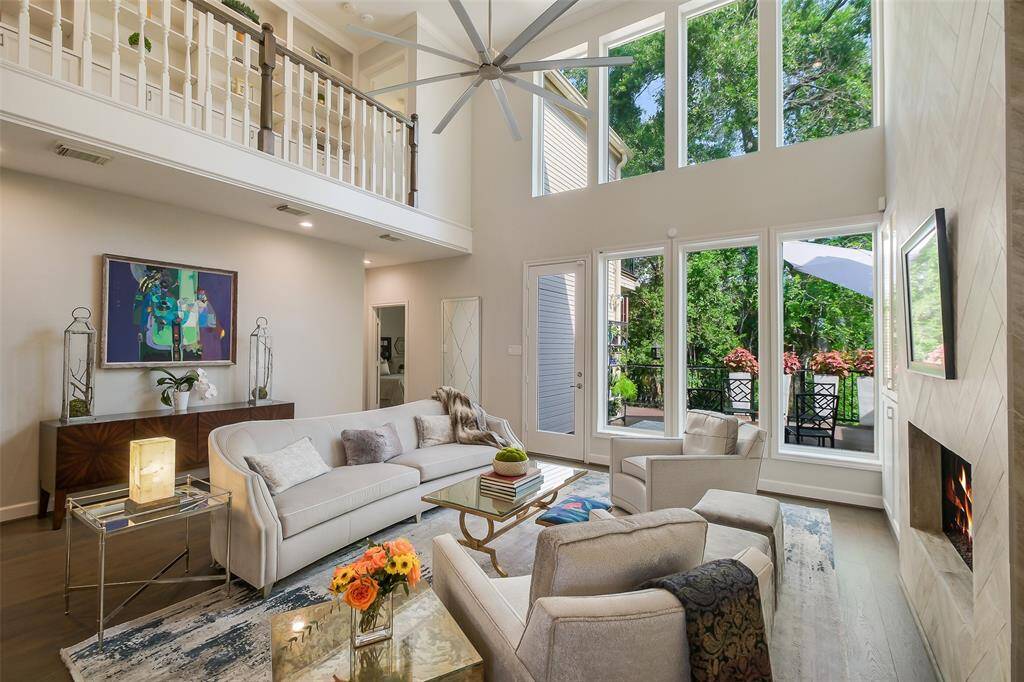 The sun-drenched living room features soaring ceilings, custom built-ins, and panoramic bayou views through floor-to-ceiling windows.