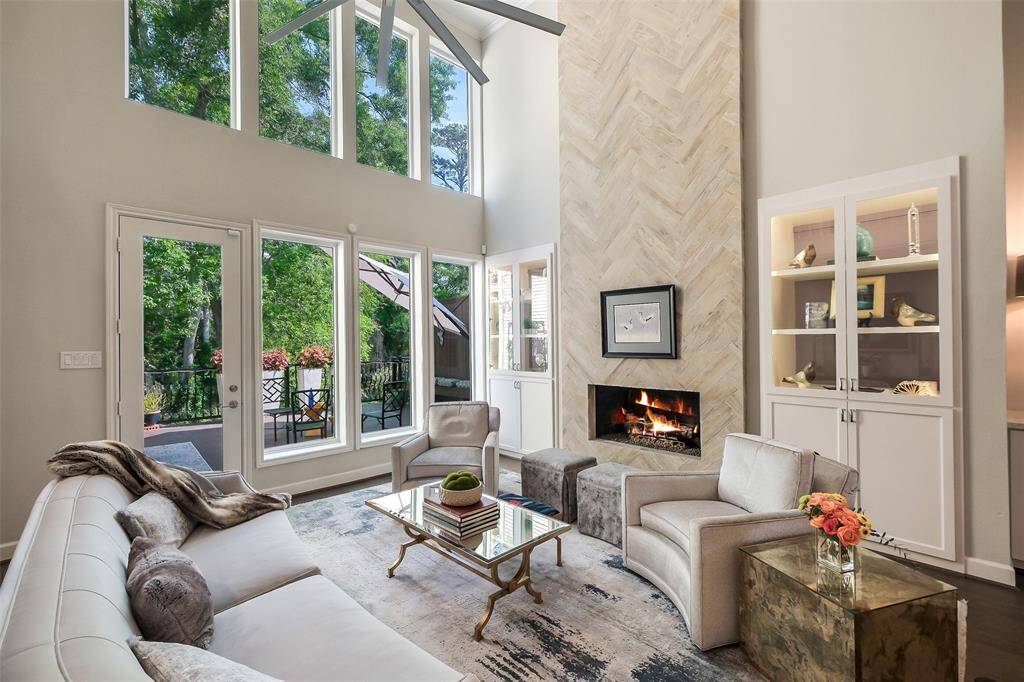 A designer herringbone-tiled fireplace anchors the space flanked by built-ins with LED lighting and an artful balance of modern and traditional elements.