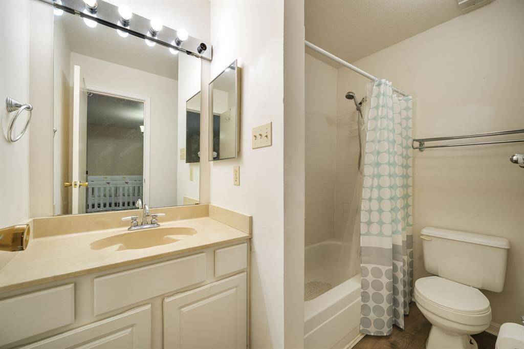 Secondary bathroom features light countertops and cabinets, custom paint, shower/tub combo with tile surround, large mirror, tile floors, sleek fixtures and modern finishes, plenty of space to accommodate any visiting family or guests.