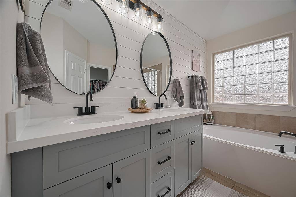 Primary bath with updated vanity, dual sinks, accent wall, soaking tub, shower and walk-in closet.